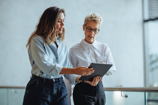 Woman and her administrative assistant use a digital tablet together in an office