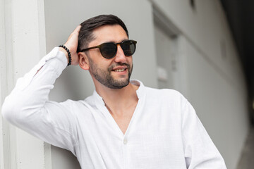 Beautiful fashion successful happy business man with vintage sunglasses in a white shirt stands...