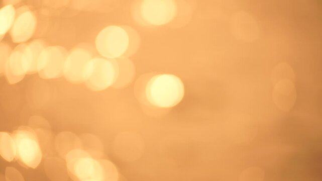 Abstract Blurred video screensaver bokeh golden sea at sunset. The sun reflects and sparkles on the waves.