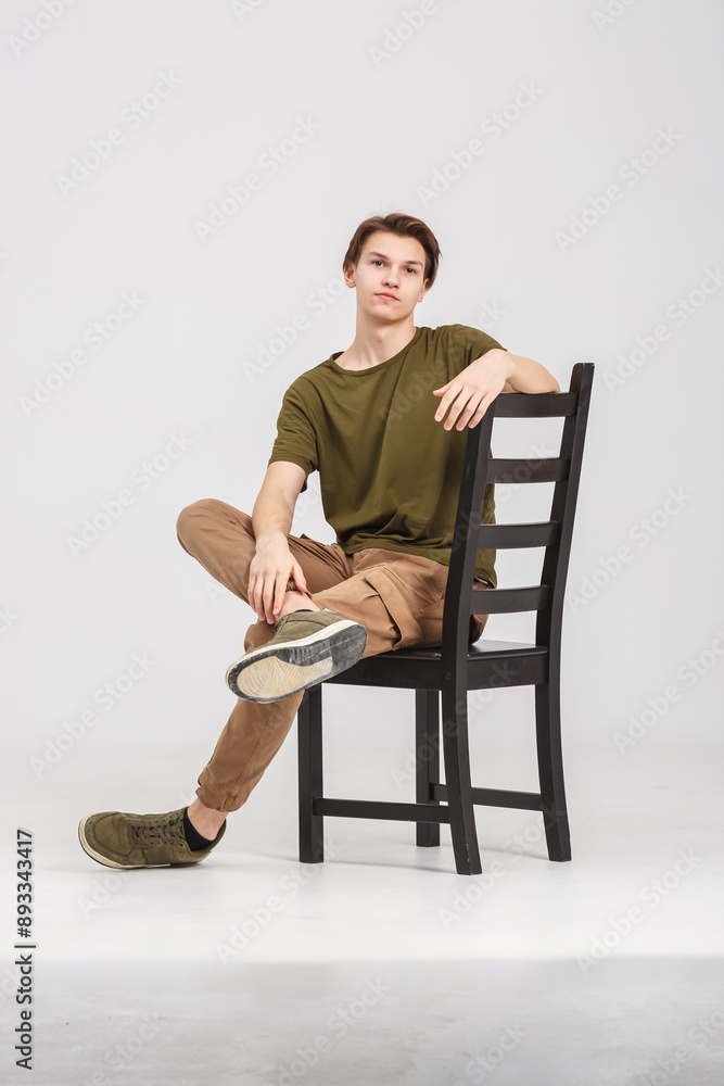 Wall mural fashion glamorous portrait of a handsome boy is posing on white gray background in studio