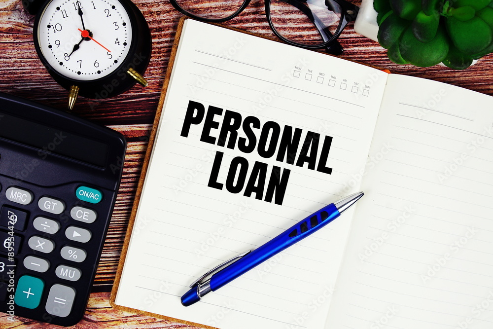 Poster personal loan text on notebook page with alarm clock and calculator top view on wooden background