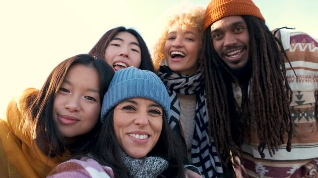 Multiracial group of friends having fun and taking a selfie together outdoors on city street. Young cheerful people hugging outside. Next gen z lifestyle concept.