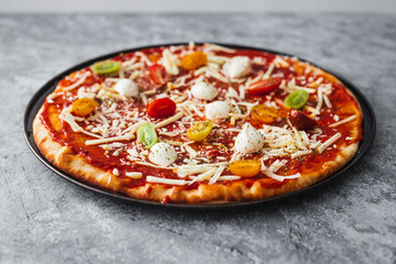 margherita pizza with cherry tomatoes before going in the oven