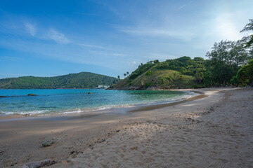 Blue sky over a small island surrounded by blue sea. White beach dotted with coconut trees. Yanui Beach, a viewpoint next to Promthep Cape and windmills, is a small beach with a split sea.