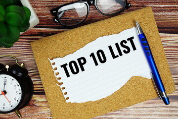 Top 10 List text written on paper torn with pen top view on wooden background