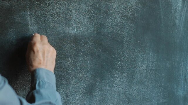 A male hand drawing E=mc2 on chalkboard. Theory of relativity physics formula