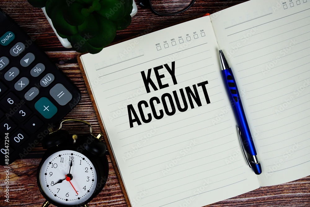 Aufkleber key account text on note page with alarm clock and calculator top view on wooden background