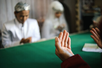 Obraz premium Selective Focus Of HAnds Praying Together Against Groom And Bride In Indonesian Wedding
