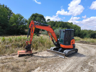 Mini escavadora de esteiras em ação na limpeza das bermas de uma estrada