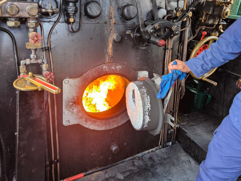 Explorando a hist&oacute;ria das locomotivas a vapor no interior da sala de m&aacute;quinas com a fornalha em chamas