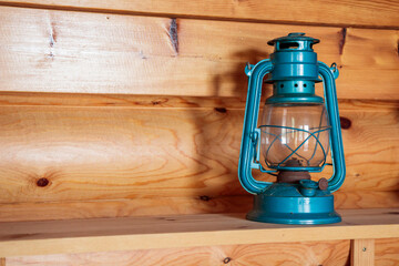 The old vintage retro blue kerosene oil lamp on a wooden shelve inside the wooden countryside house...