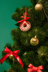 Close-up of Christmas tree decorated with colorful ornaments, including pink frosted donuts against green studio background. Concept of winter holiday, Christmas, New Year, celebration