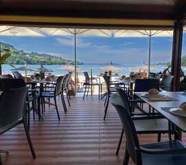 beach bar with empty tables and chairs, and views of the sea