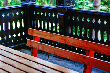 Wooden bench sits on a porch with a wooden balustrade. The scene is peaceful and serene, with the...