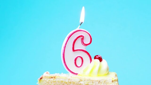 Birthday 6 years old. Cake with burning candle in the form of number 6. Bright blue background with copy space.