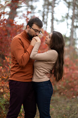 Fototapeta premium caucasian couple in love on a date in an autumn forest. man kisses his girlfriend's hand. concept: happy relationships, dating on the internet. propose in nature. 