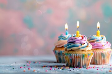 Colorful cupcakes with lit candles for a birthday celebration on a pastel background. Festive and delicious treats adorned with frosting, sprinkles, and decorative cupcake toppers