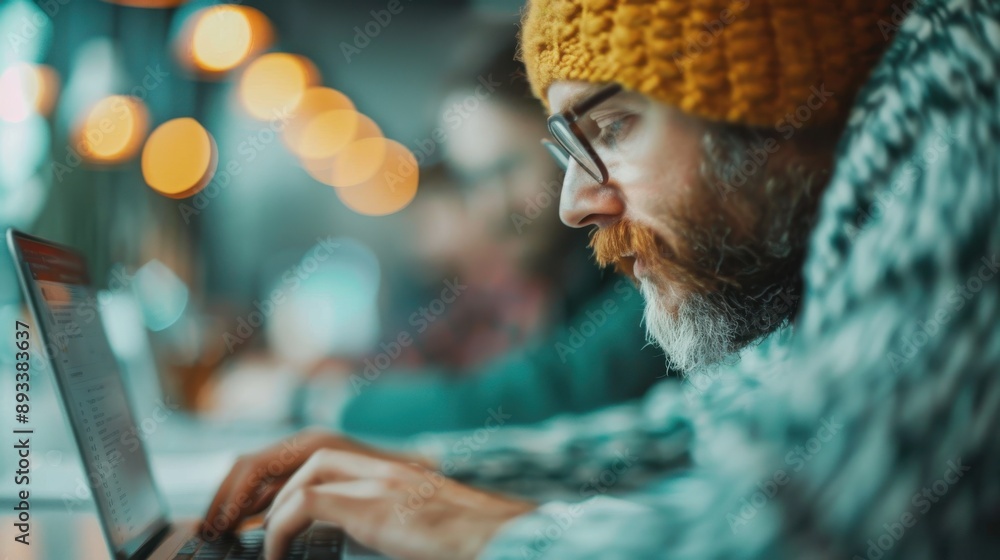 Poster this shows a man wearing a knitted sweater, typing on a laptop amidst an event with a bokeh backgrou
