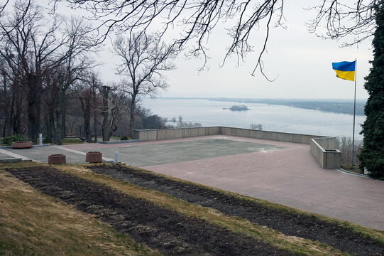 The flag of Ukraine on the background of the cloudy Dnipro river 
