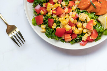 Fresh salmon toss spicy gochujang sauce with healthy green salad kale, corn and tomato on plate.