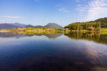 Fototapeta premium Beautiful landscape with reflection of mountain range on water at Tha Khoei reservoir in Ratchaburi, Thailand.