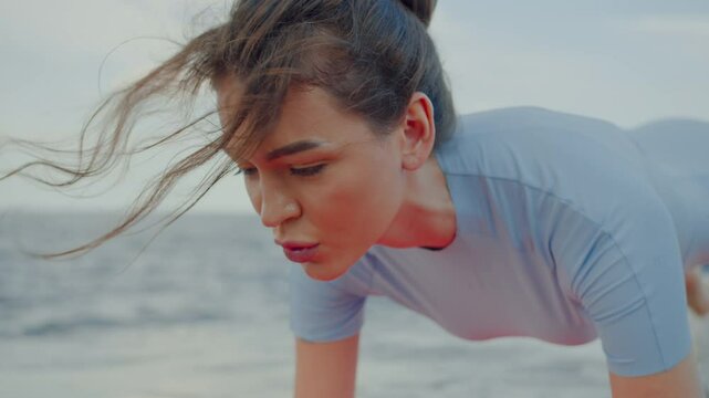 Concentrated female closing eyes while standing in plank
