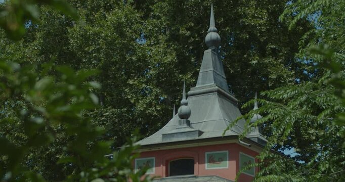 Beautiful slow motion shot of the dome of the famous &ldquo;Casita del Pescador del Parque El Retiro&rdquo; in Madrid, Spain in the morning sunlight and seen between tree branches.