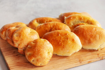 Homemade patties filled with egg and spring onion on a wooden board. Russian cuisine.