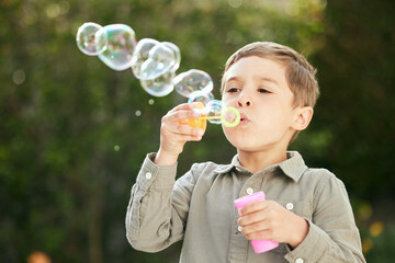 Outdoor, bubbles and blow of boy for playful, excitement and entertainment for childhood in park....