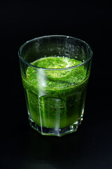 黒背景にガラスのコップにグリーンスムージ