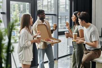 A group of coworkers enjoy a pizza break in a modern office.