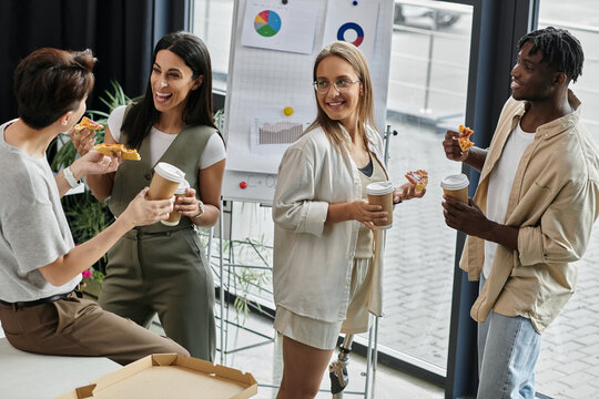 Four colleagues enjoy a casual lunch break with pizza and coffee.