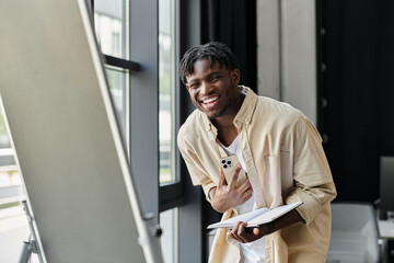 Young man smiling with notebook and smartphone, discussing new idea in modern office