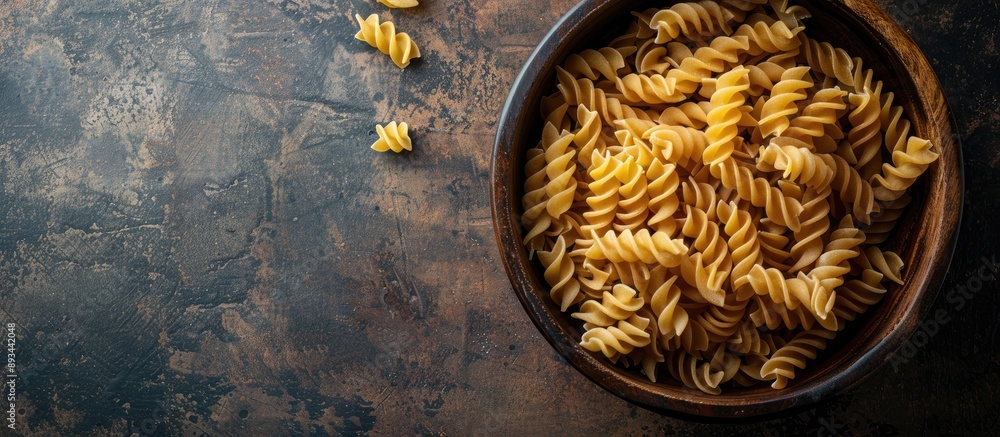 Poster Top view of uncooked Creste di Gallo pasta presented in a wooden bowl on a dark vintage backdrop with room for text or other graphics in the image. with copy space image