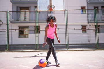 Cute african woman learning to dribble a basketball alone