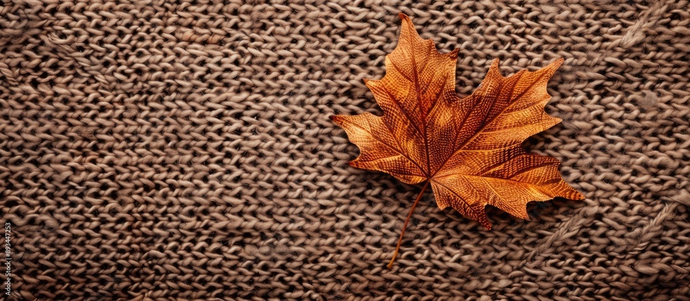 Poster Autumn themed background featuring a maple leaf on a knitted surface with space for additional images