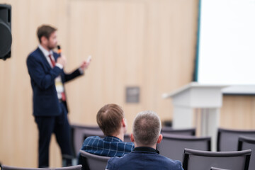 Speaker giving a business presentation to attentive audience in conference room. Professional...