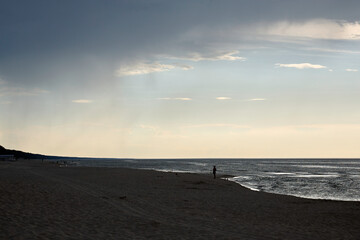 Meerlandschaft mit einer spazierenden Person. Dramatische Abendstimmung.