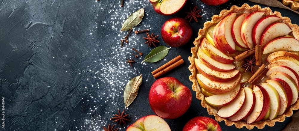 Leinwandbilder Close up top view of a homemade fruit tart with golden crust featuring whole and halved apples cinnamon sticks and anise seeds against a background with copy space image