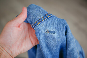 A woman holds jeans with a hole.