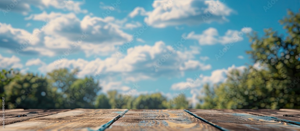 Poster focused on an empty brown wooden table against a blurred blue sky background with bokeh effects perf