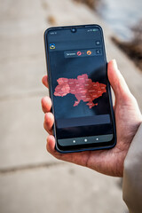 Air alarm map in smartphone in woman hand in Ukraine