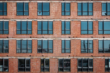 Brick wall of modern skyscraper building under construction, instaled windows texture