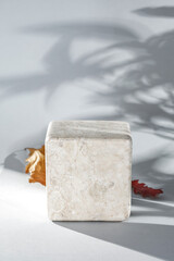 Image composition of white table background with square stone pedestal with copy space. Natural daily sunlight.