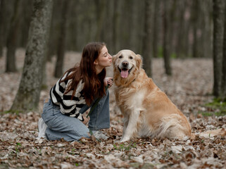 Teenage Girl Sits With Golden Retriever In Park During Autumn