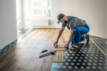 Professional carpenter worker joining vinyl or laminate floor covering at home renovation