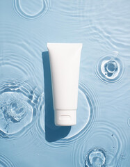 White cosmetic tube gracefully floating on rippled water. Beauty and skincare product promotion