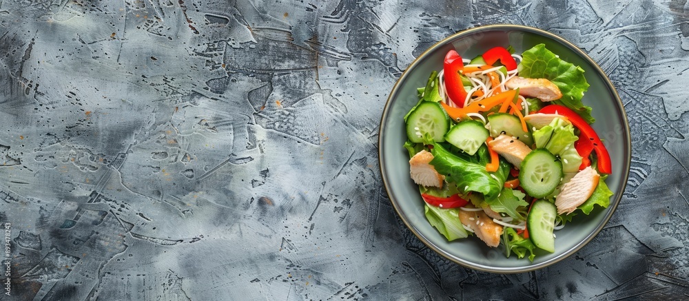 Poster A salad with Chinese noodles chicken peppers and cucumber displayed on a textured stone background with empty space for more elements in the image. copy space available