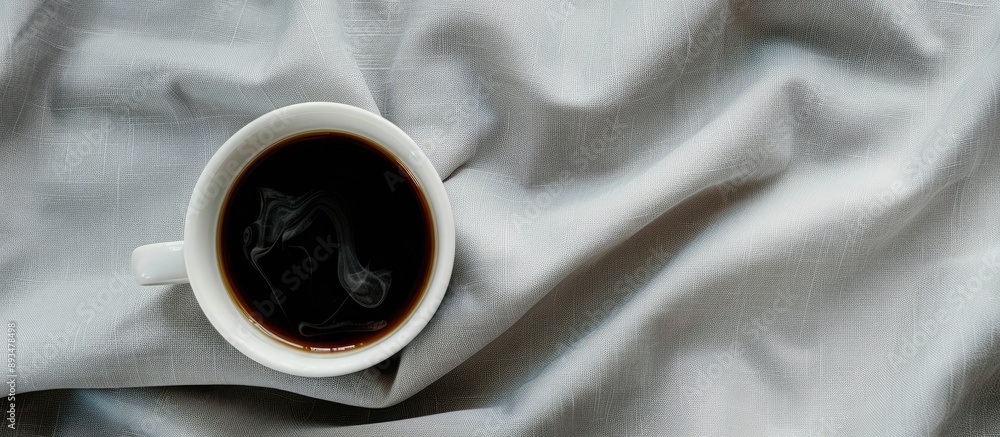 Poster a top down view of a hot cup of black coffee in a white mug on a gray tablecloth serving as a copy s