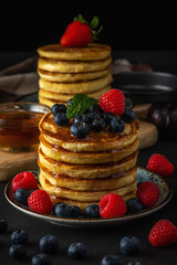 Delicious pancakes with fresh berries on dark background. Food concept.